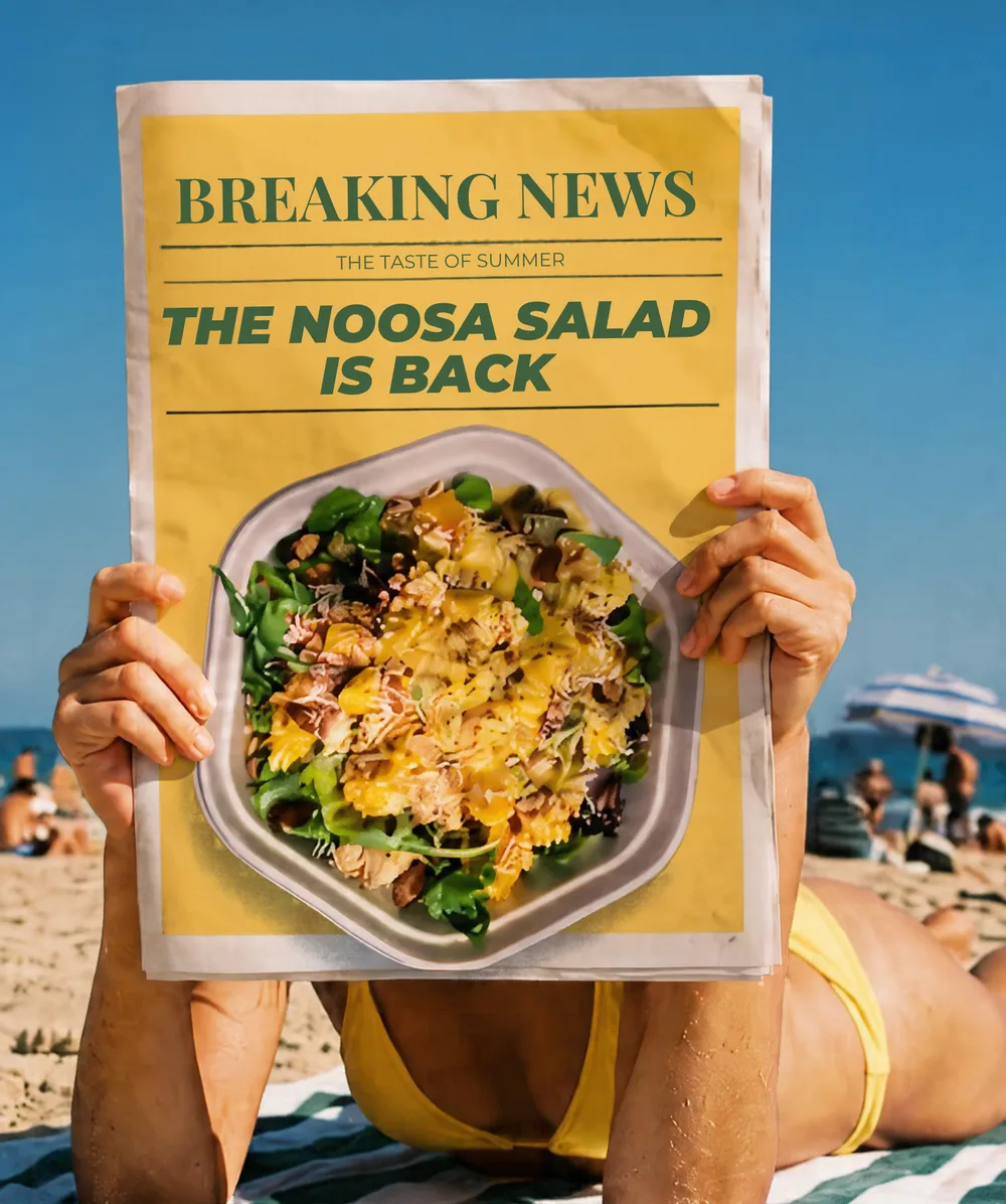 Beachgoer reading a newspaper headlined: The Noosa Salad is back